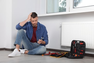 Man holding wrench near box with tools indoors