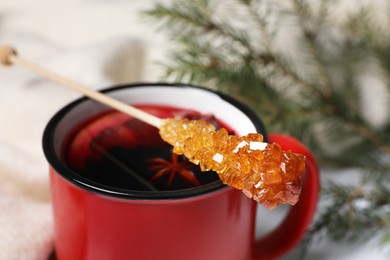 Photo of Stick with sugar crystals and cup of drink, closeup view