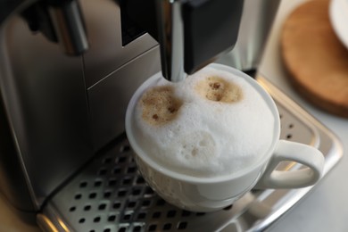 Modern coffee machine with cup of cappuccino, closeup
