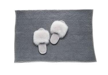 Soft grey bath mat and slippers isolated on white, top view