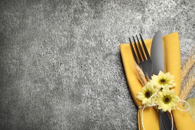 Cutlery, spikelets and flowers on grey table, flat lay with space for text. Thanksgiving Day celebration