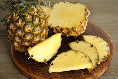 Photo of Whole and cut pineapples on wooden table, closeup
