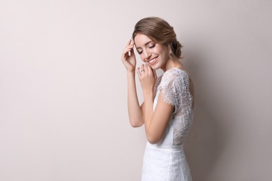 Young bride with elegant wedding hairstyle on beige background. Space for text