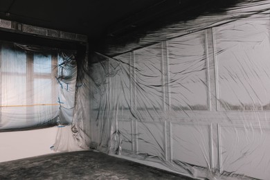 Photo of Windows and wall covered with plastic film in empty room