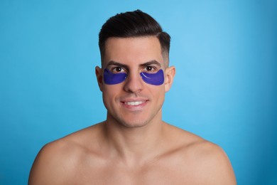 Man with under eye patches on light blue background