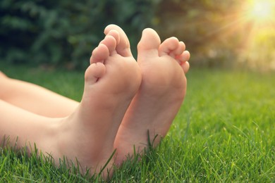 Teenage girl sitting barefoot on green grass outdoors, closeup