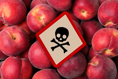 Skull and crossbones sign on ripe peaches, top view. Be careful - toxic
