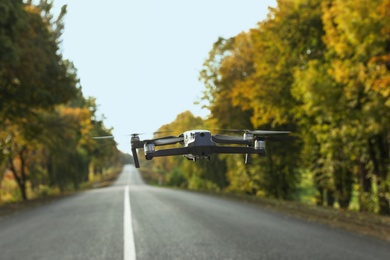 Modern drone with camera above asphalt highway on autumn day