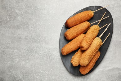 Delicious deep fried corn dogs with board on light grey table, top view. Space for text