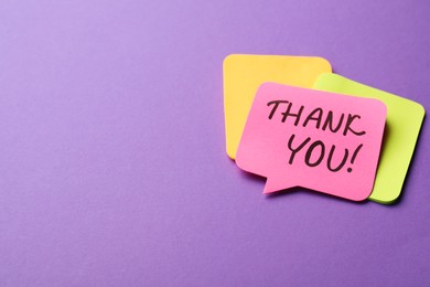 Photo of Pink paper note with phrase Thank You on purple background, space for text