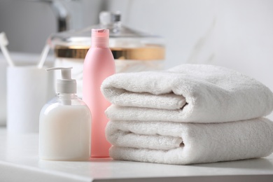 Folded towels and toiletries on white table in bathroom