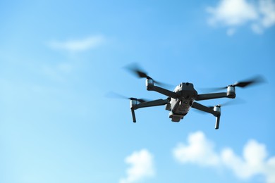 Modern drone with camera flying in sky on sunny day