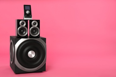 Modern powerful audio speaker system with remote on pink background, space for text