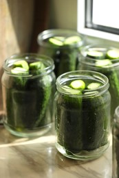 Photo of Glass jars with fresh cucumbers on table, closeup. Canning vegetables