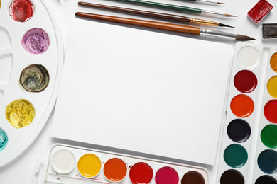 Watercolor paints, brushes and blank paper with space for design on white background, flat lay