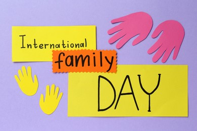 Happy International Family Day. Cards with text and paper hands cutouts on violet background, flat lay