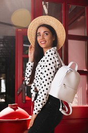 Beautiful young woman with stylish backpack and hat outdoors