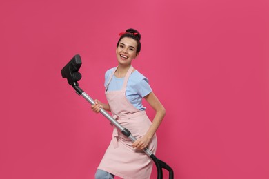 Housewife with vacuum cleaner on pink background