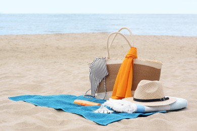 Blue towel, bag and beach accessories on sandy seashore, space for text