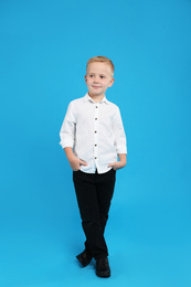 Full length portrait of cute little boy on light blue background