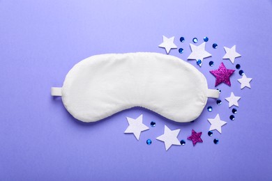 Photo of Soft sleep mask, confetti in shape of stars and sequins on purple background, flat lay