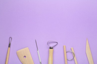 Set of clay modeling tools on violet background, flat lay. Space for text