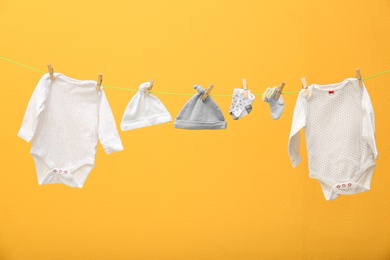 Children's clothes on laundry line against color background