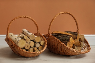 Wicker baskets with firewood near brown wall indoors