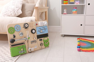 Busy board on floor indoors, space for text. Baby sensory toy