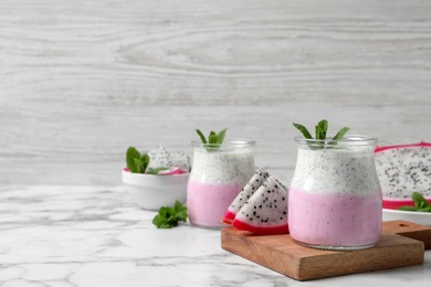 Delicious pitahaya smoothie, fruits and fresh mint on white marble table, space for text