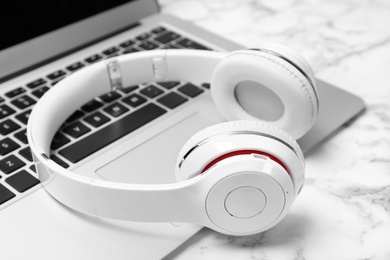Modern headphones and laptop on table, closeup