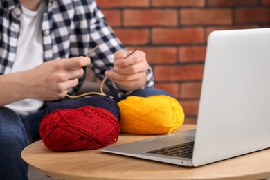 Photo of Man learning to knit with online course at home, closeup. Time for hobby