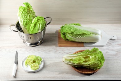 Whole and cut fresh ripe Chinese cabbages on white wooden table