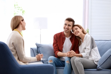 Young happy couple after therapy session with family psychologist indoors