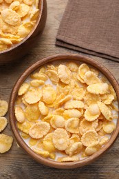 Tasty cornflakes with milk in bowls on wooden table, flat lay