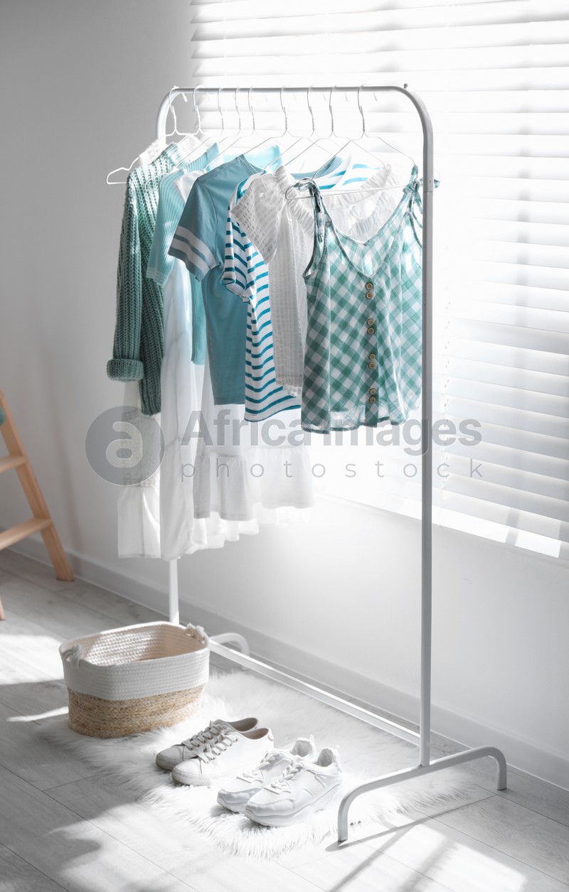 Photo of Rack with stylish women's clothes indoors. Interior design