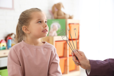 Speech therapist using logopedic probes on session with little girl in office