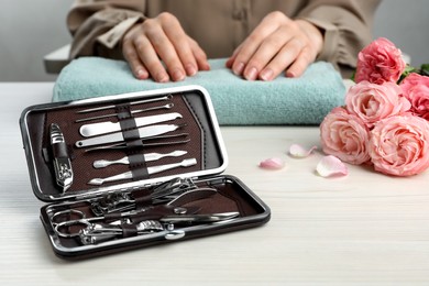 Photo of Woman at white wooden table, focus on case with manicure set