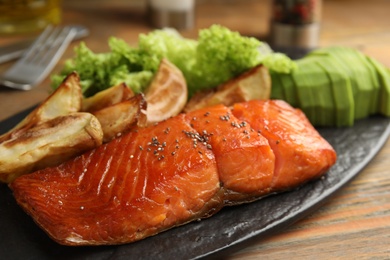 Photo of Tasty cooked salmon and vegetables served on wooden table, closeup. Healthy meals from air fryer