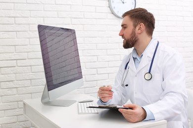 Pediatrician consulting patient online at table in clinic