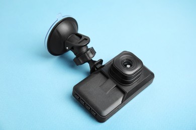 Modern car dashboard camera with suction mount on light blue background