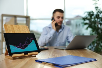 Broker working in office, focus on tablet with chart. Forex trading