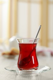 Photo of Glass of traditional Turkish tea on white wooden table indoors