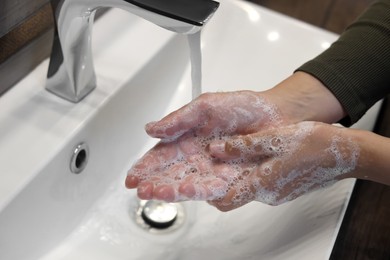 Photo of Woman washing hands in sink, closeup view