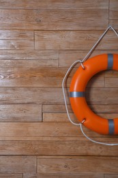 Orange lifebuoy on wooden background, space for text. Rescue equipment
