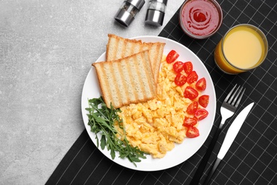 Delicious scrambled eggs served on light grey table, flat lay