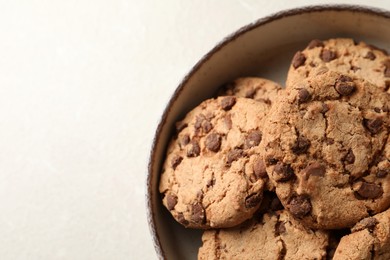 Delicious chocolate chip cookies in bowl on light table, top view. Space for text