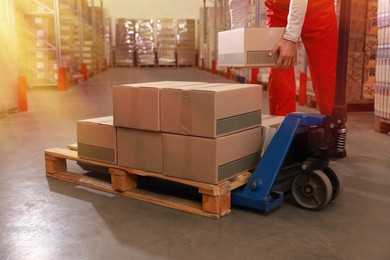 Worker taking cardboard box from pallet in warehouse, closeup