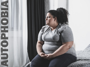 Depressed overweight woman sitting alone on bed at home. Autophobia - fear of isolation