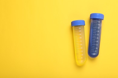 Photo of Test tubes with colorful liquids on yellow background, flat lay and space for text. Kids chemical experiment set